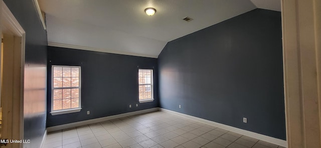 tiled spare room featuring vaulted ceiling