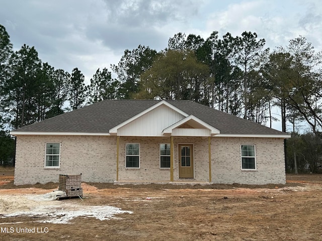 view of front facade featuring brick siding and roof with shingles