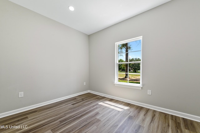 empty room featuring wood finished floors, baseboards, and recessed lighting