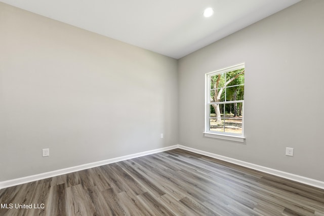empty room featuring dark wood-type flooring, baseboards, and recessed lighting