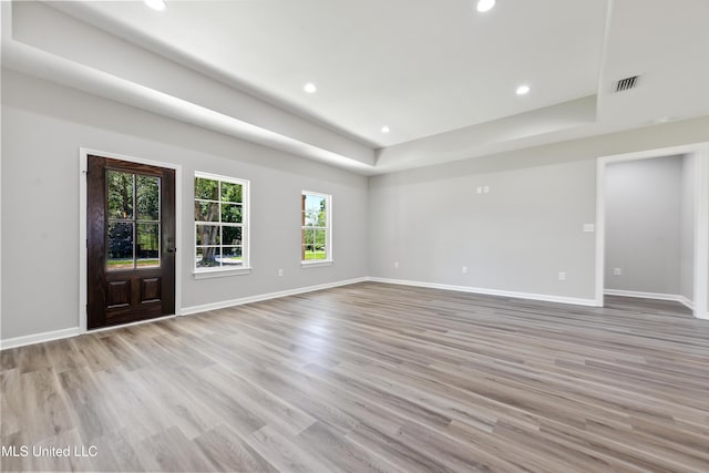unfurnished room with recessed lighting, light wood-type flooring, baseboards, and a tray ceiling