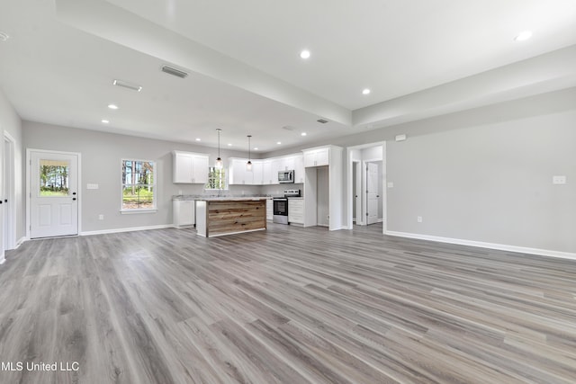 unfurnished living room with light wood-style flooring, baseboards, and recessed lighting