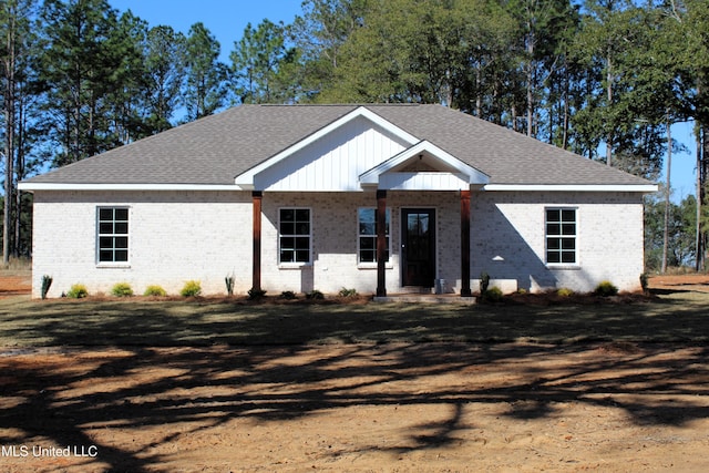 view of front of house with brick siding and roof with shingles