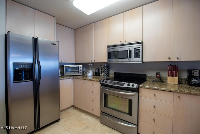 kitchen with a toaster, light stone countertops, light tile patterned flooring, and stainless steel appliances