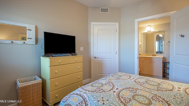 bedroom featuring visible vents, ensuite bathroom, and a sink