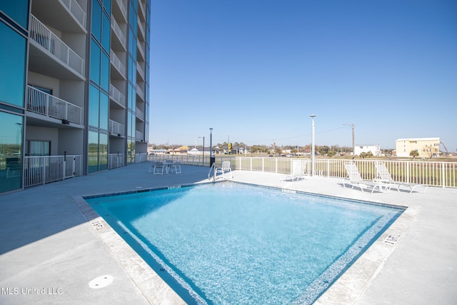 community pool with a patio area and fence