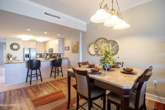 dining area featuring visible vents, crown molding, baseboards, recessed lighting, and light wood-style floors