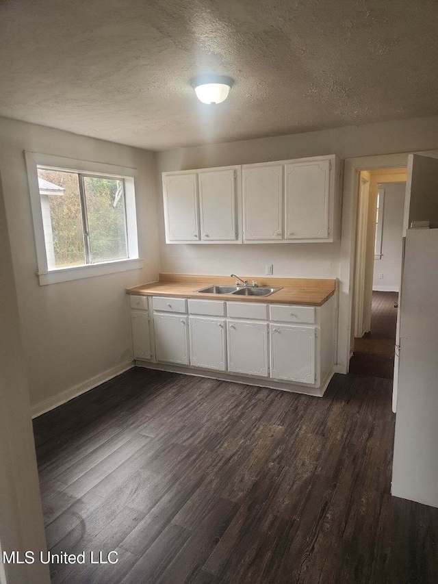 kitchen featuring white cabinetry, sink, dark wood-type flooring, and a textured ceiling