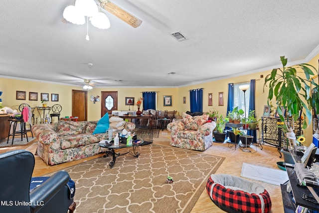 living room with a wealth of natural light, ornamental molding, a textured ceiling, and ceiling fan