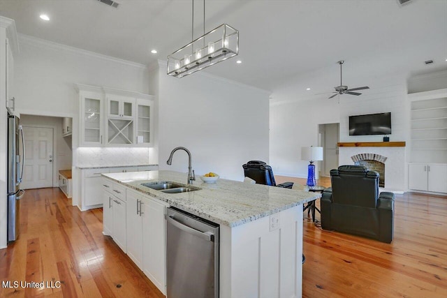 kitchen featuring stainless steel appliances, a center island with sink, sink, white cabinets, and light hardwood / wood-style floors