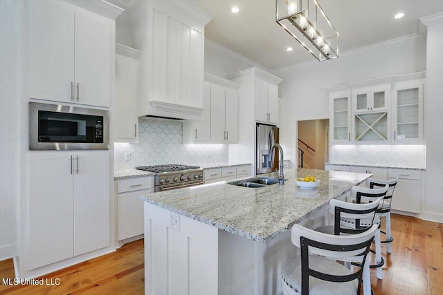 kitchen with stainless steel appliances, sink, light wood-type flooring, and white cabinets