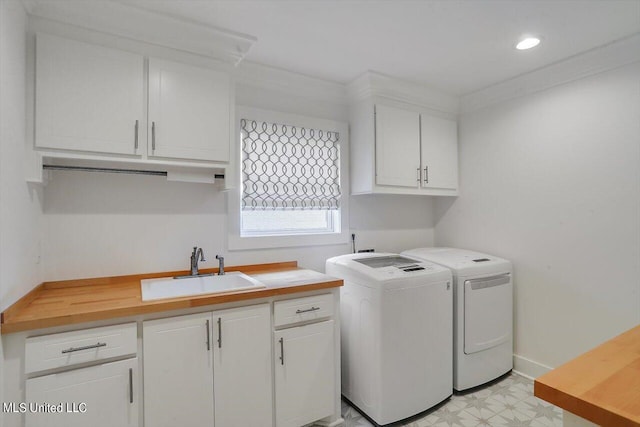 clothes washing area featuring sink, washing machine and dryer, and cabinets