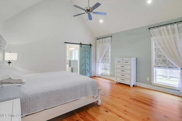 bedroom featuring a barn door, high vaulted ceiling, wood-type flooring, and ceiling fan