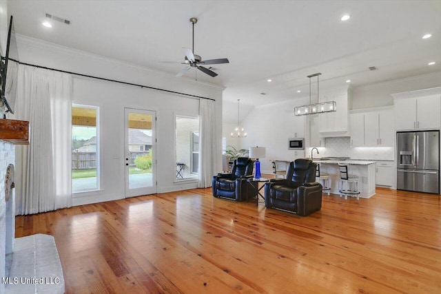 living room featuring sink, crown molding, ceiling fan with notable chandelier, and light hardwood / wood-style floors