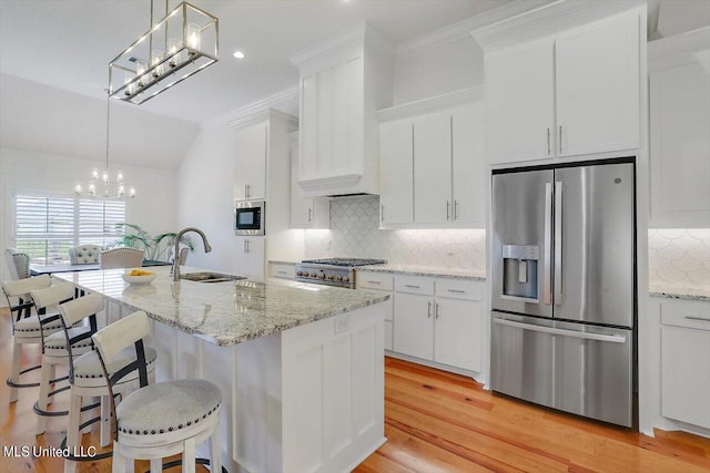 kitchen with stainless steel appliances, sink, an island with sink, and white cabinets