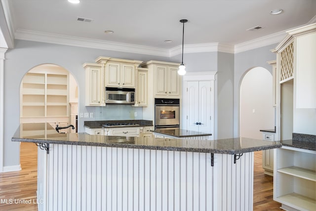 kitchen with pendant lighting, stainless steel appliances, light hardwood / wood-style flooring, and dark stone counters