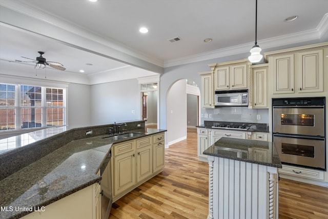 kitchen featuring sink, cream cabinetry, dark stone counters, and appliances with stainless steel finishes