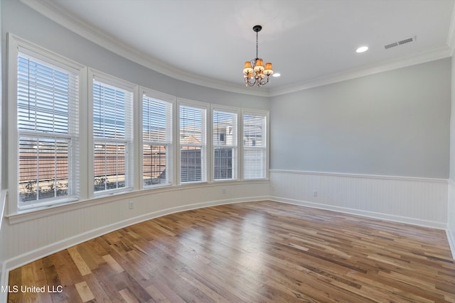 spare room with hardwood / wood-style flooring, ornamental molding, and an inviting chandelier