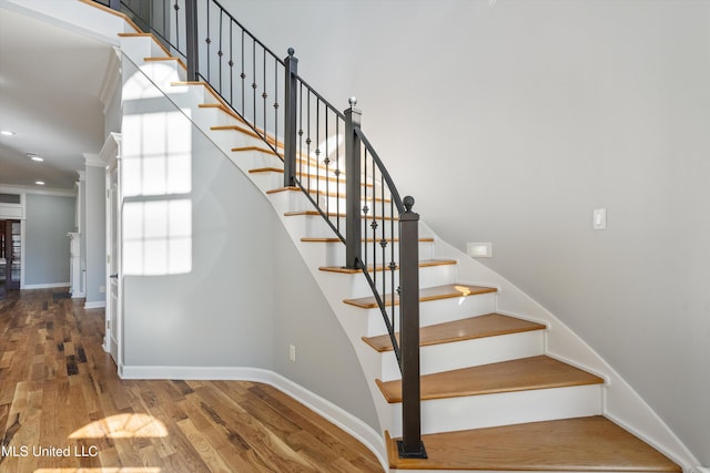 stairs with hardwood / wood-style floors and ornamental molding