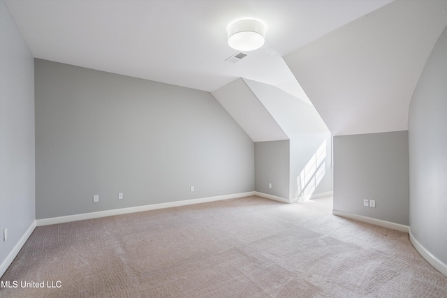 additional living space featuring light colored carpet and lofted ceiling