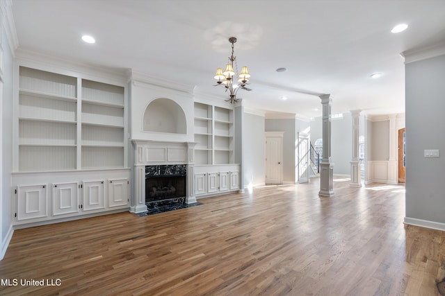 unfurnished living room with crown molding, a high end fireplace, hardwood / wood-style flooring, and ornate columns