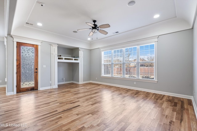 unfurnished bedroom with a raised ceiling, light hardwood / wood-style floors, ceiling fan, and multiple windows