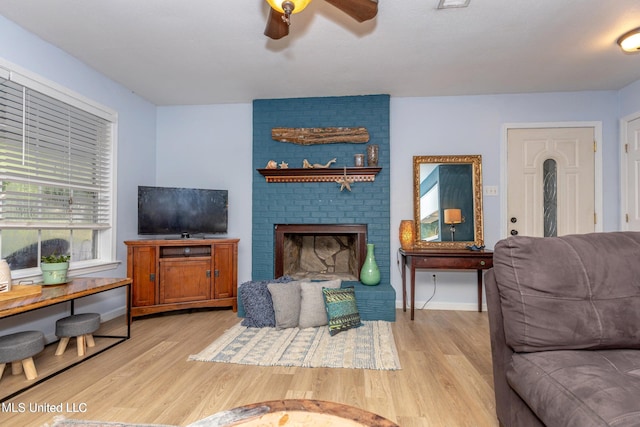 living room with ceiling fan, light wood-type flooring, and a fireplace