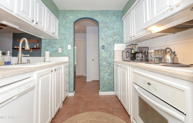 kitchen with white cabinetry, sink, backsplash, white appliances, and dark tile patterned flooring