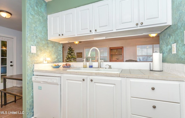 kitchen featuring white dishwasher, sink, light tile patterned floors, white cabinetry, and kitchen peninsula