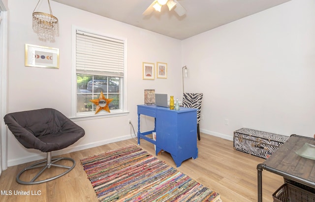 office featuring ceiling fan with notable chandelier and light hardwood / wood-style flooring