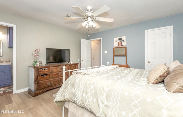 bedroom with ceiling fan, light wood-type flooring, and ensuite bath