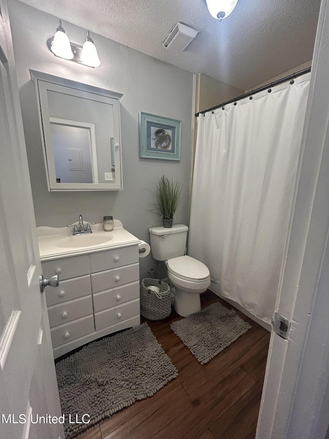 3620 Cochran Ave, Moss Point, MS 39562 - full bath featuring wood finished floors, toilet, vanity, a textured ceiling, and curtained shower