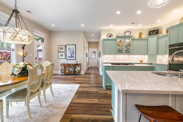 kitchen featuring green cabinetry, visible vents, a sink, stainless steel gas cooktop, and dark wood-style flooring
