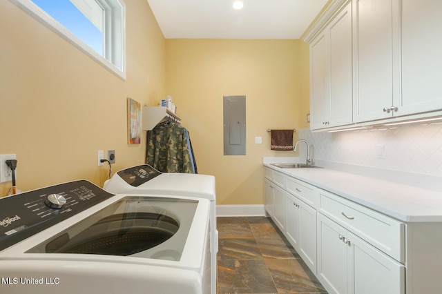 laundry area featuring electric panel, stone tile flooring, washing machine and dryer, baseboards, and cabinet space
