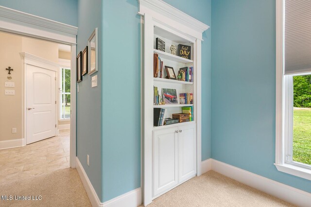 corridor with plenty of natural light, baseboards, and light colored carpet