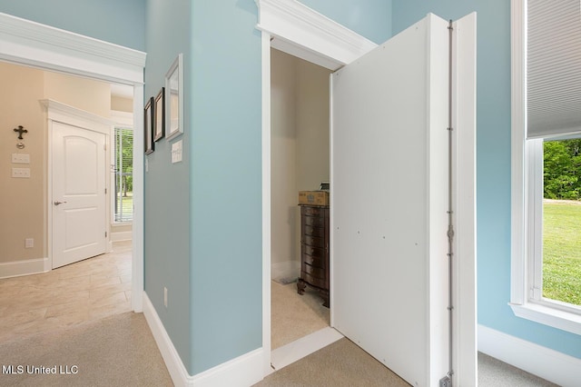 corridor featuring baseboards and light colored carpet