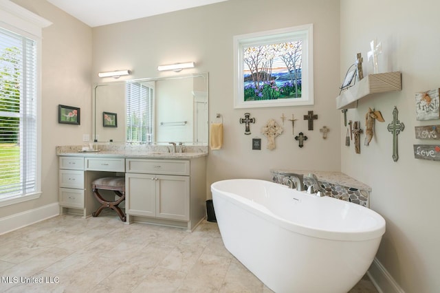 full bathroom featuring vanity, baseboards, a soaking tub, and plenty of natural light