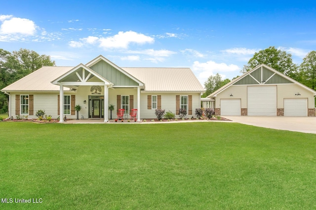 view of front of house with metal roof, covered porch, a garage, an outdoor structure, and a front yard