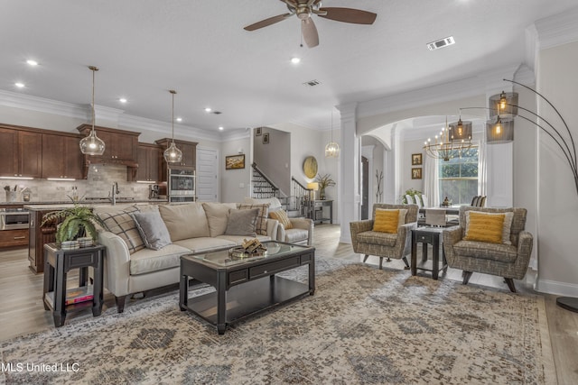 5705 Via Toscana, Ocean Springs, MS 39564 - living area featuring a chandelier, stairway, ceiling fan, crown molding, and ornate columns