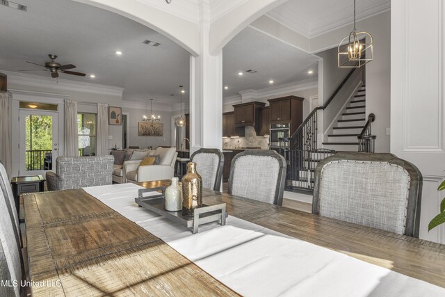 5705 Via Toscana, Ocean Springs, MS 39564 - dining room featuring ceiling fan, arched walkways, a chandelier, wood finished floors, and crown molding