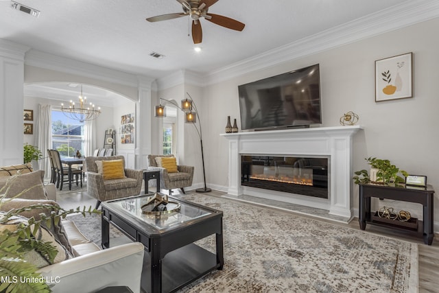 5705 Via Toscana, Ocean Springs, MS 39564 - living room featuring a chandelier, a ceiling fan, crown molding, a glass covered fireplace, and arched walkways