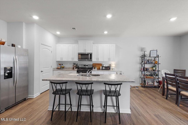 2250 Hyacinth Ln, Hernando, MS 38632 - kitchen with appliances with stainless steel finishes, a center island with sink, dark wood-style floors, a kitchen breakfast bar, and recessed lighting