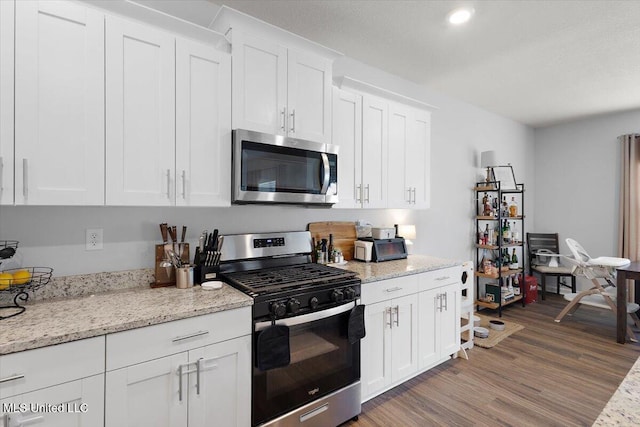 2250 Hyacinth Ln, Hernando, MS 38632 - kitchen with stainless steel appliances, wood finished floors, white cabinetry, and light stone countertops