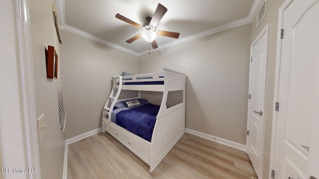 bedroom featuring ceiling fan, ornamental molding, light hardwood / wood-style floors, and a textured ceiling