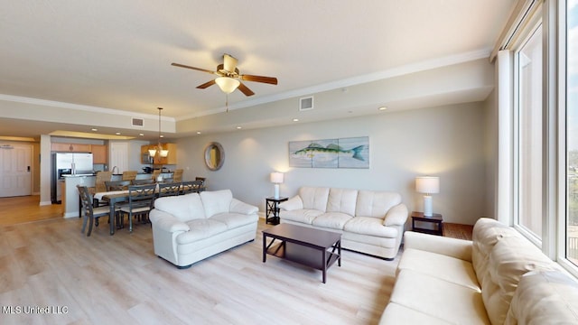 living room with ceiling fan, ornamental molding, and light wood-type flooring