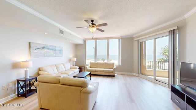 living room featuring ceiling fan, ornamental molding, a textured ceiling, and light wood-type flooring