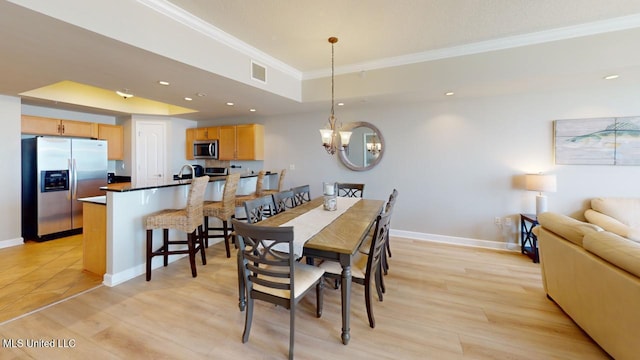 dining space featuring ornamental molding, a raised ceiling, light hardwood / wood-style floors, and a notable chandelier