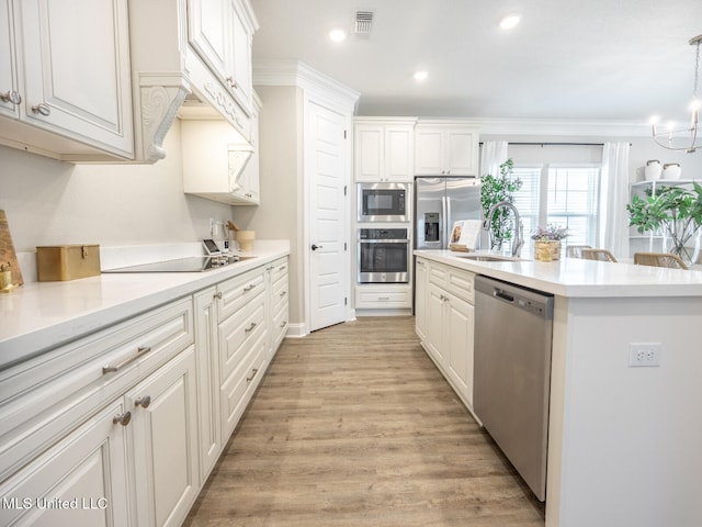 kitchen featuring a sink, white cabinetry, light countertops, appliances with stainless steel finishes, and decorative light fixtures