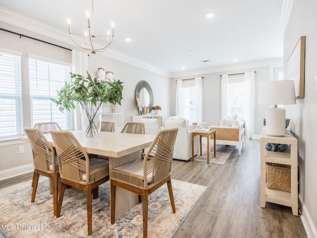 dining space featuring baseboards, crown molding, light wood finished floors, and an inviting chandelier