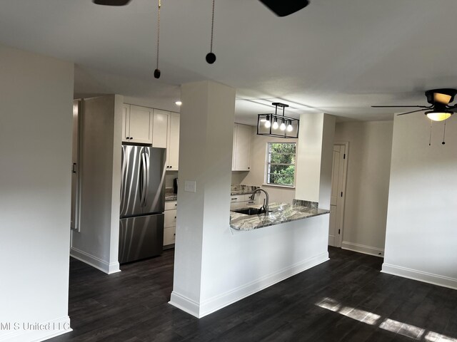 kitchen featuring stainless steel refrigerator, white cabinetry, sink, hanging light fixtures, and dark wood-type flooring